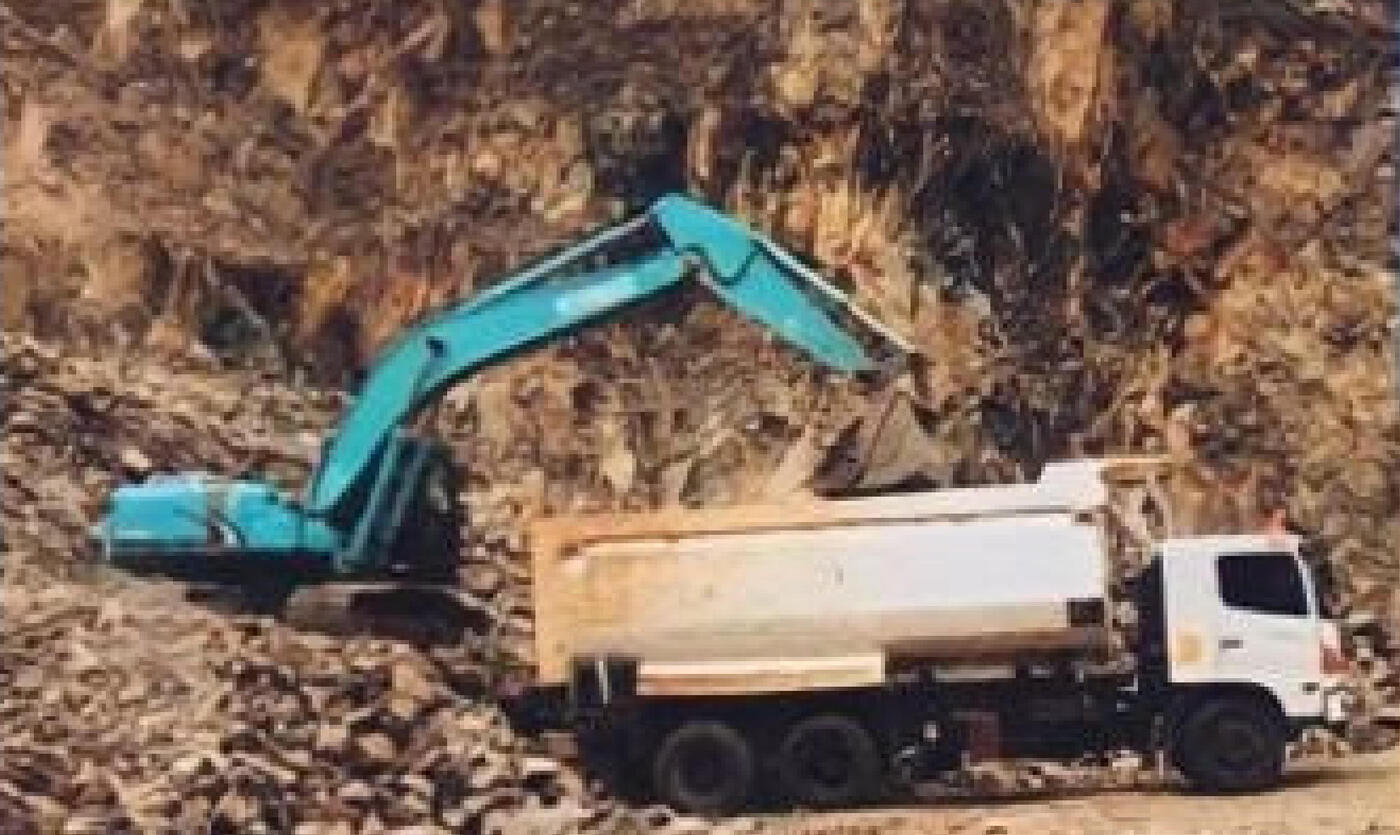Excavator memuat batu ke dump truck