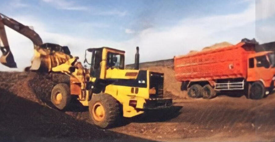 Wheel loader mengisi dump truck di area tambang